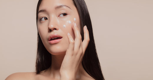 An Asian woman applying moisturizer with probiotics to protect her skin from pollution