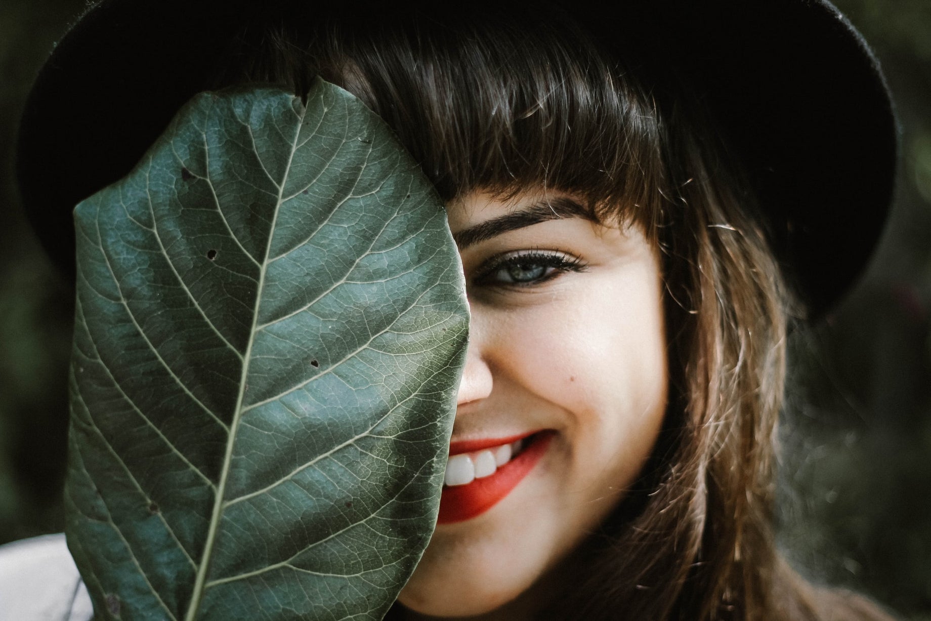 Smiling woman with healthy, glowing skin holding a leaf