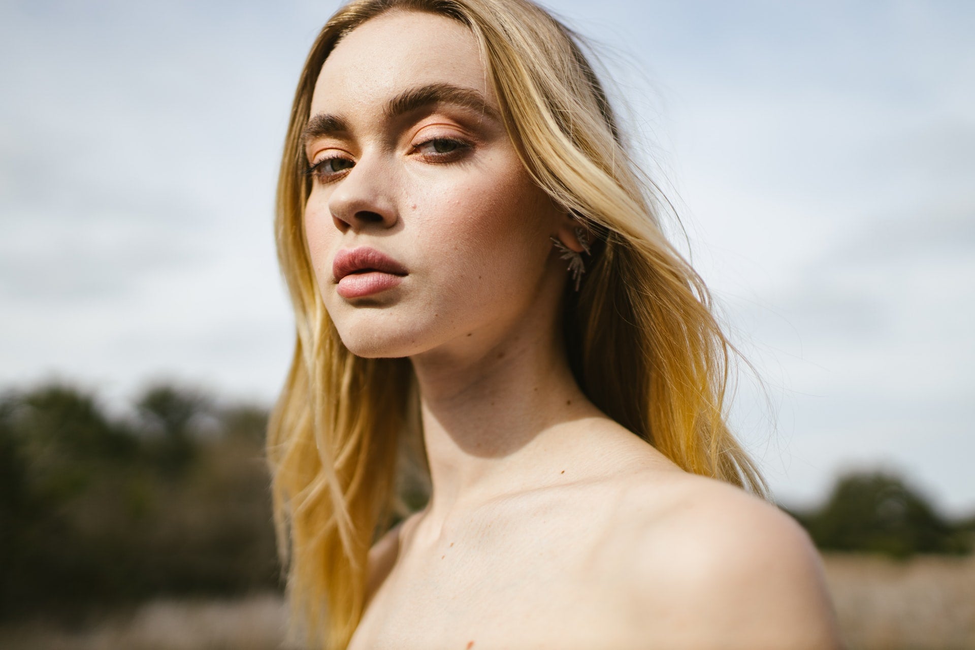 confident woman standing in nature with clear, glowing skin