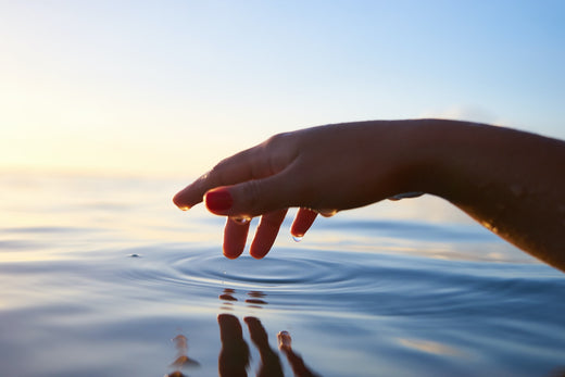 Hand touching water, symbolizing skin hydration